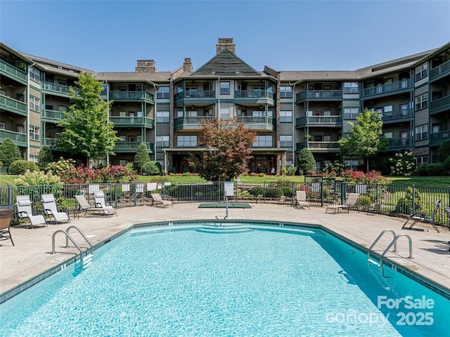 pool with a patio area and fence