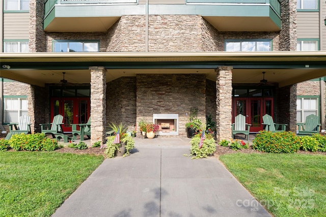 view of front of property with brick siding, ceiling fan, exterior fireplace, and a front lawn