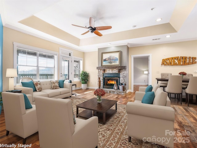 living area featuring a tray ceiling, crown molding, and wood finished floors