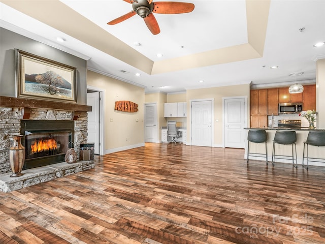 living room with a fireplace, baseboards, ornamental molding, dark wood-style floors, and a raised ceiling