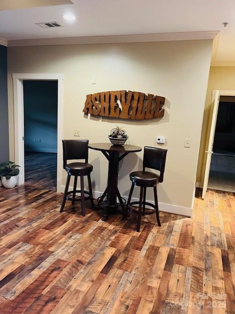 bar with ornamental molding, hardwood / wood-style floors, and baseboards