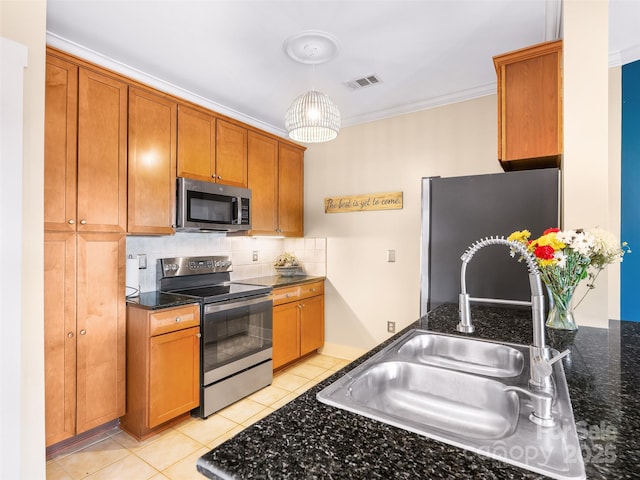 kitchen with a sink, visible vents, appliances with stainless steel finishes, backsplash, and pendant lighting