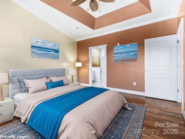 bedroom with dark wood-style floors, crown molding, a raised ceiling, ensuite bath, and baseboards