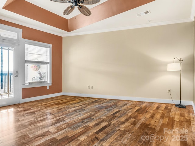 unfurnished room with ornamental molding, a raised ceiling, visible vents, and wood finished floors