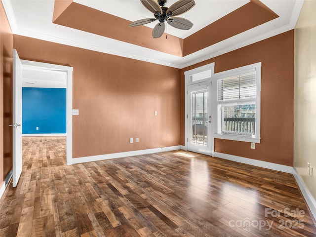 spare room featuring ornamental molding, a raised ceiling, and wood finished floors