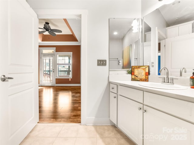 bathroom with a tray ceiling, ceiling fan, vanity, baseboards, and tile patterned floors