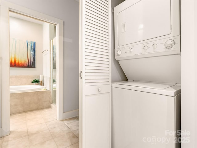 clothes washing area with light tile patterned floors, laundry area, and stacked washing maching and dryer