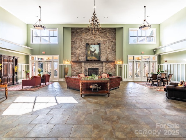 living room with stone finish floor, a fireplace, a towering ceiling, and baseboards