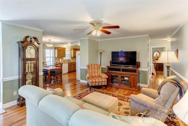 living room with light hardwood / wood-style flooring, ceiling fan, and ornamental molding