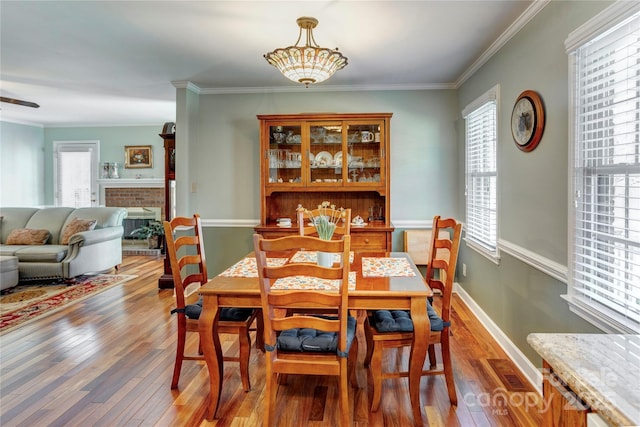 dining space with ornamental molding, dark wood-type flooring, and a fireplace