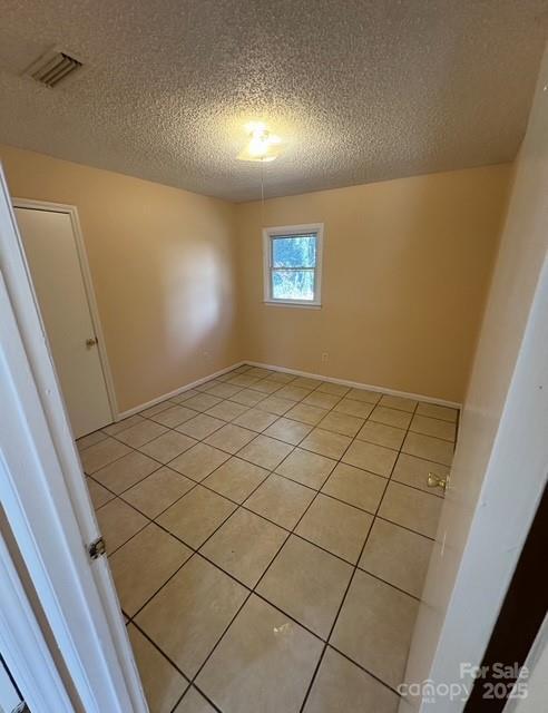 tiled spare room with a textured ceiling