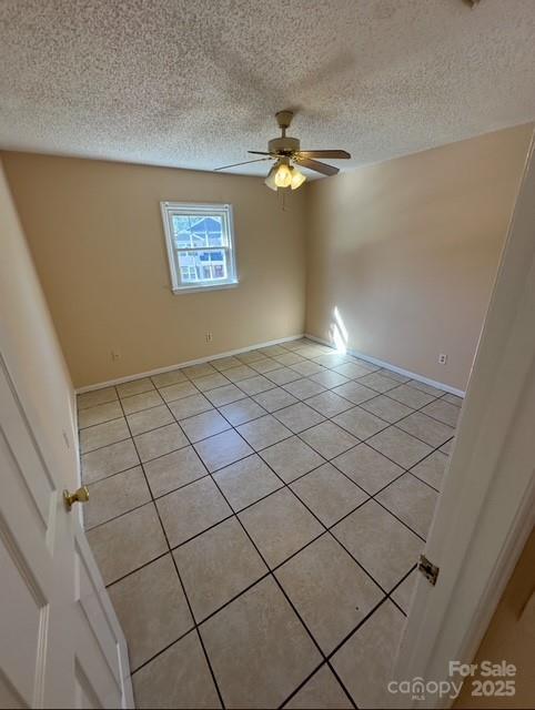 unfurnished room with a textured ceiling, light tile patterned flooring, and ceiling fan