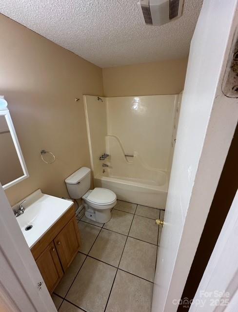 full bathroom with vanity, washtub / shower combination, a textured ceiling, tile patterned flooring, and toilet