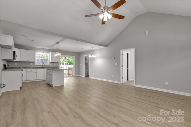 kitchen featuring white cabinetry, light wood-type flooring, a kitchen island, sink, and ceiling fan with notable chandelier