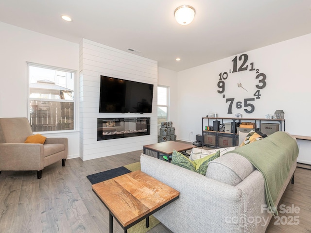 living room with a fireplace, wood finished floors, visible vents, and recessed lighting