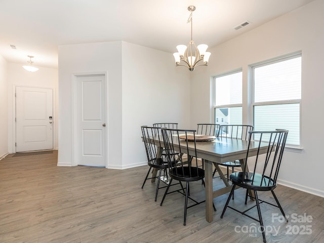 dining space featuring an inviting chandelier, visible vents, baseboards, and dark wood-type flooring