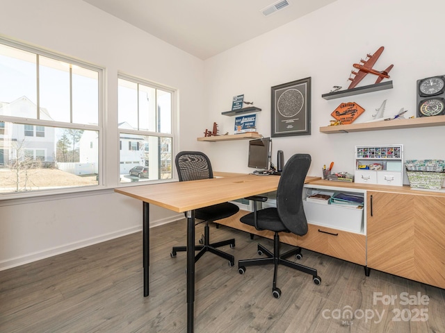 office space with baseboards, visible vents, and wood finished floors