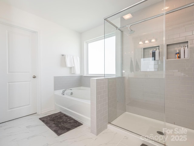 bathroom with marble finish floor, a bath, and a stall shower