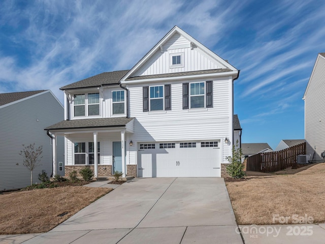 view of front of property featuring central air condition unit, board and batten siding, fence, a garage, and driveway