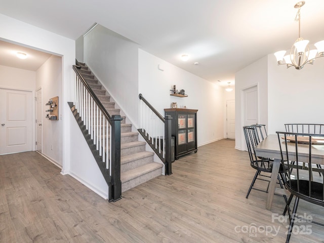 interior space with light wood-style floors, baseboards, stairs, and a chandelier