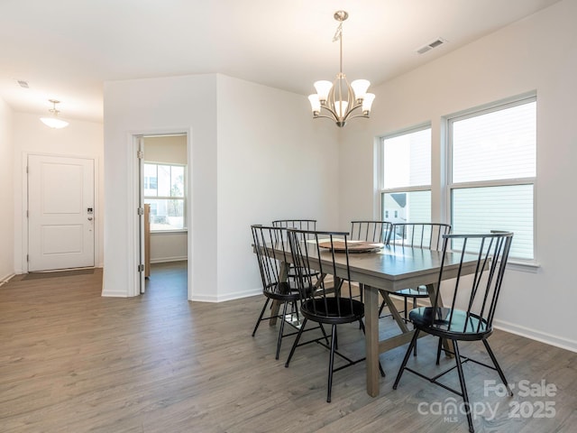 dining area featuring a chandelier, dark wood-style flooring, visible vents, and baseboards