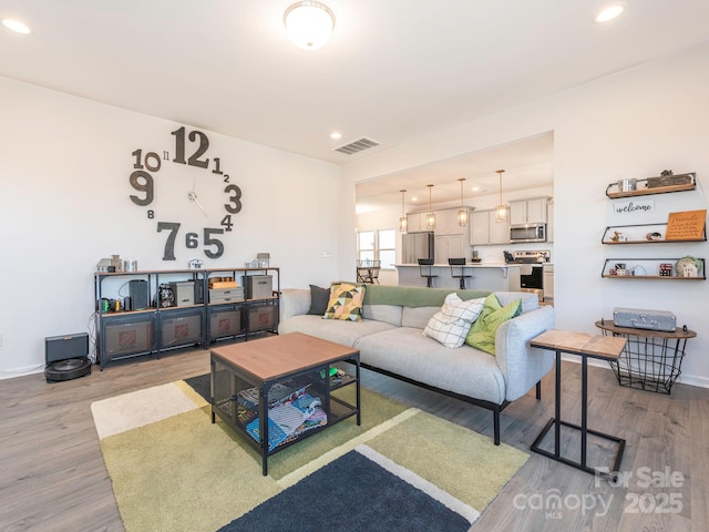 living area featuring recessed lighting, visible vents, baseboards, and wood finished floors