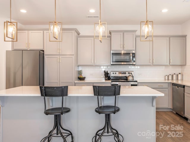 kitchen with stainless steel appliances, decorative light fixtures, and a center island