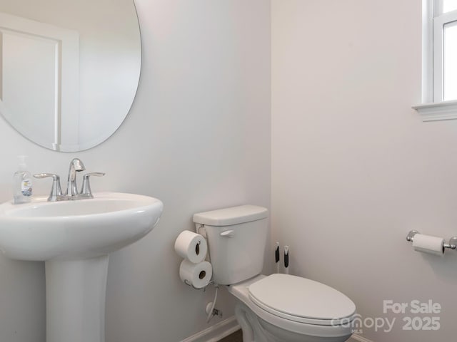 bathroom with toilet, baseboards, and a sink