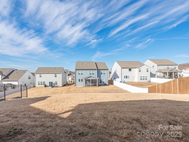 rear view of property with a yard, fence, and a residential view