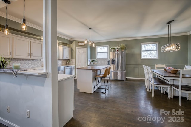 kitchen with stainless steel appliances, a kitchen bar, decorative light fixtures, and plenty of natural light