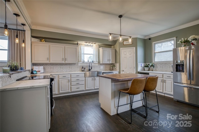 kitchen with sink, white cabinetry, a kitchen island, pendant lighting, and stainless steel appliances