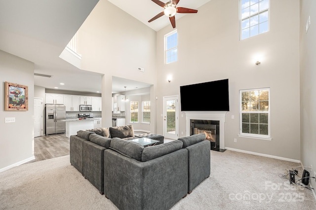 living room featuring baseboards, light carpet, and a fireplace with flush hearth