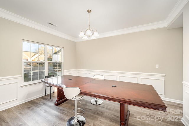 home office with crown molding, visible vents, an inviting chandelier, and light wood finished floors