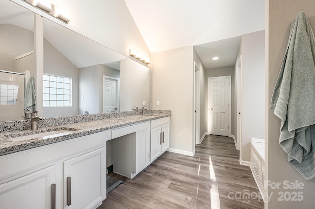 bathroom with double vanity, wood finished floors, baseboards, a sink, and lofted ceiling