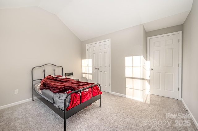 bedroom featuring vaulted ceiling, a closet, light carpet, and baseboards