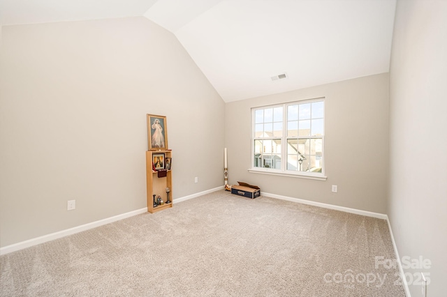 carpeted spare room featuring high vaulted ceiling, baseboards, and visible vents