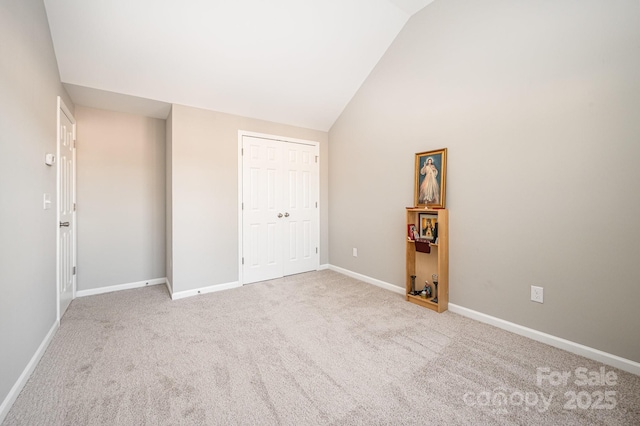 unfurnished bedroom with baseboards, vaulted ceiling, and light carpet