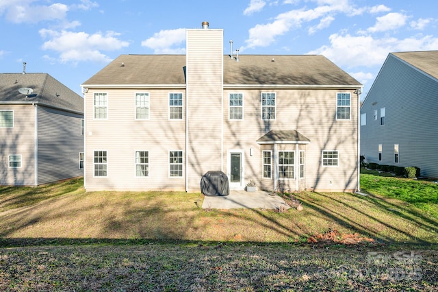 back of property featuring a lawn, a patio, and a chimney