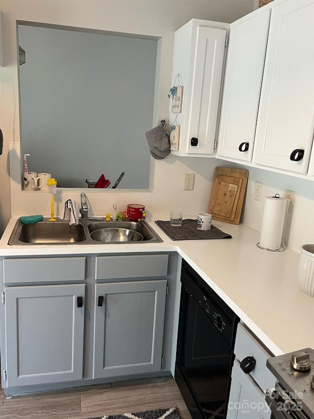 kitchen featuring white cabinets, dishwasher, wood finished floors, light countertops, and a sink