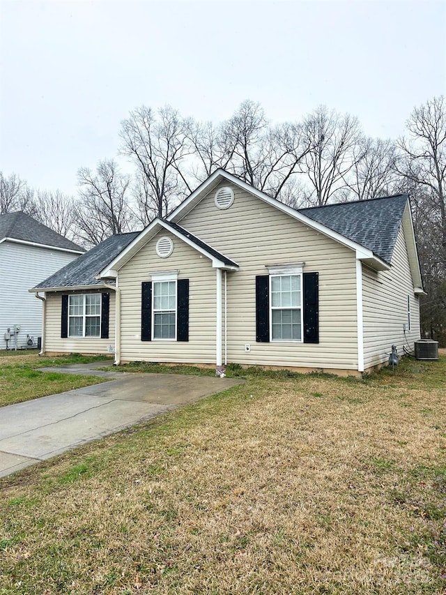 ranch-style home with a front lawn, a shingled roof, and central air condition unit