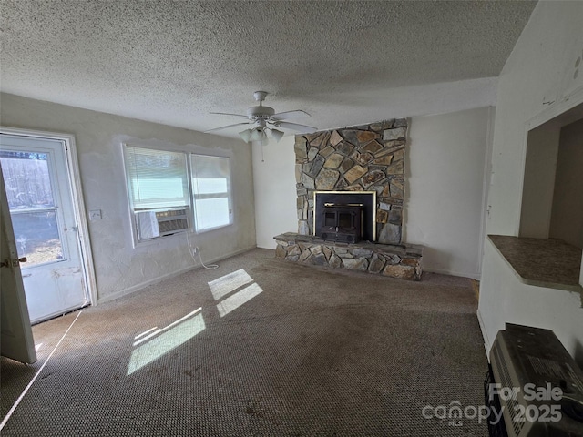 unfurnished living room with cooling unit, carpet flooring, a stone fireplace, and a textured ceiling