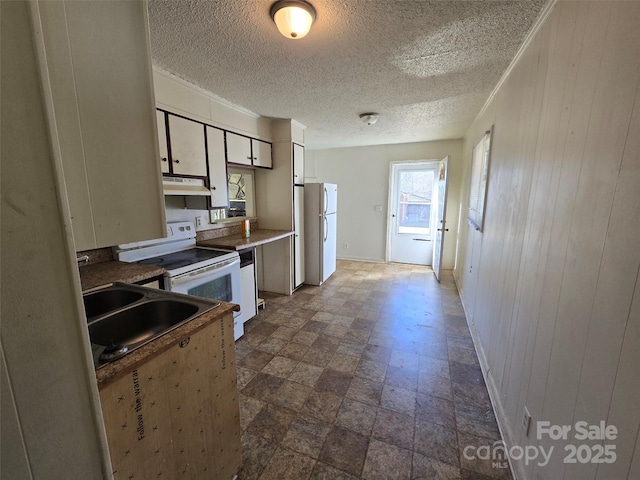 kitchen featuring white cabinetry, white appliances, sink, and wood walls