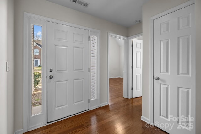 foyer entrance featuring dark wood-type flooring, a wealth of natural light, visible vents, and baseboards