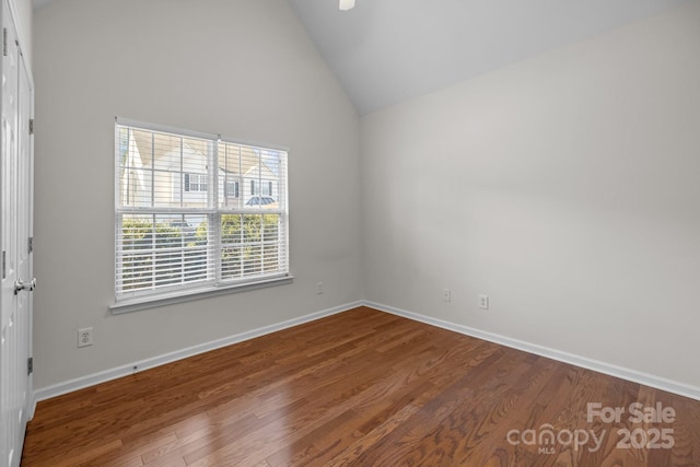 empty room with high vaulted ceiling, baseboards, and wood finished floors