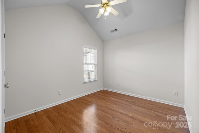 unfurnished room featuring lofted ceiling, wood finished floors, visible vents, baseboards, and a ceiling fan