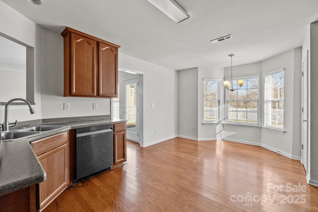 kitchen featuring dark countertops, dark wood-type flooring, hanging light fixtures, stainless steel dishwasher, and a sink