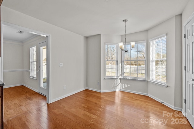 unfurnished dining area with baseboards, visible vents, an inviting chandelier, and wood finished floors