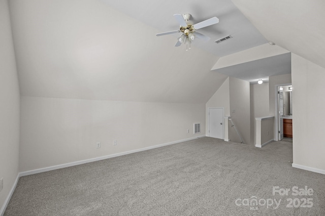 additional living space with light carpet, visible vents, and vaulted ceiling