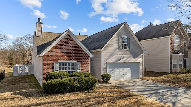 traditional-style home with a garage, concrete driveway, a chimney, fence, and brick siding