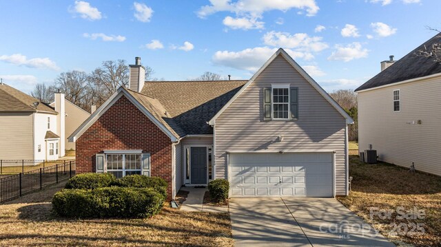 traditional-style home featuring brick siding, a chimney, central air condition unit, concrete driveway, and fence